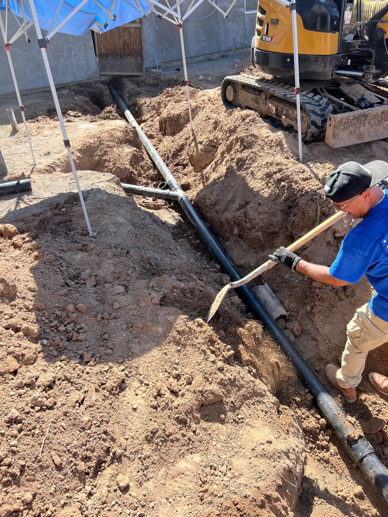 A man is digging a hole in the dirt with a shovel.