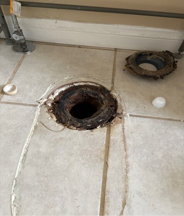 A hole in the floor next to a toilet flange.