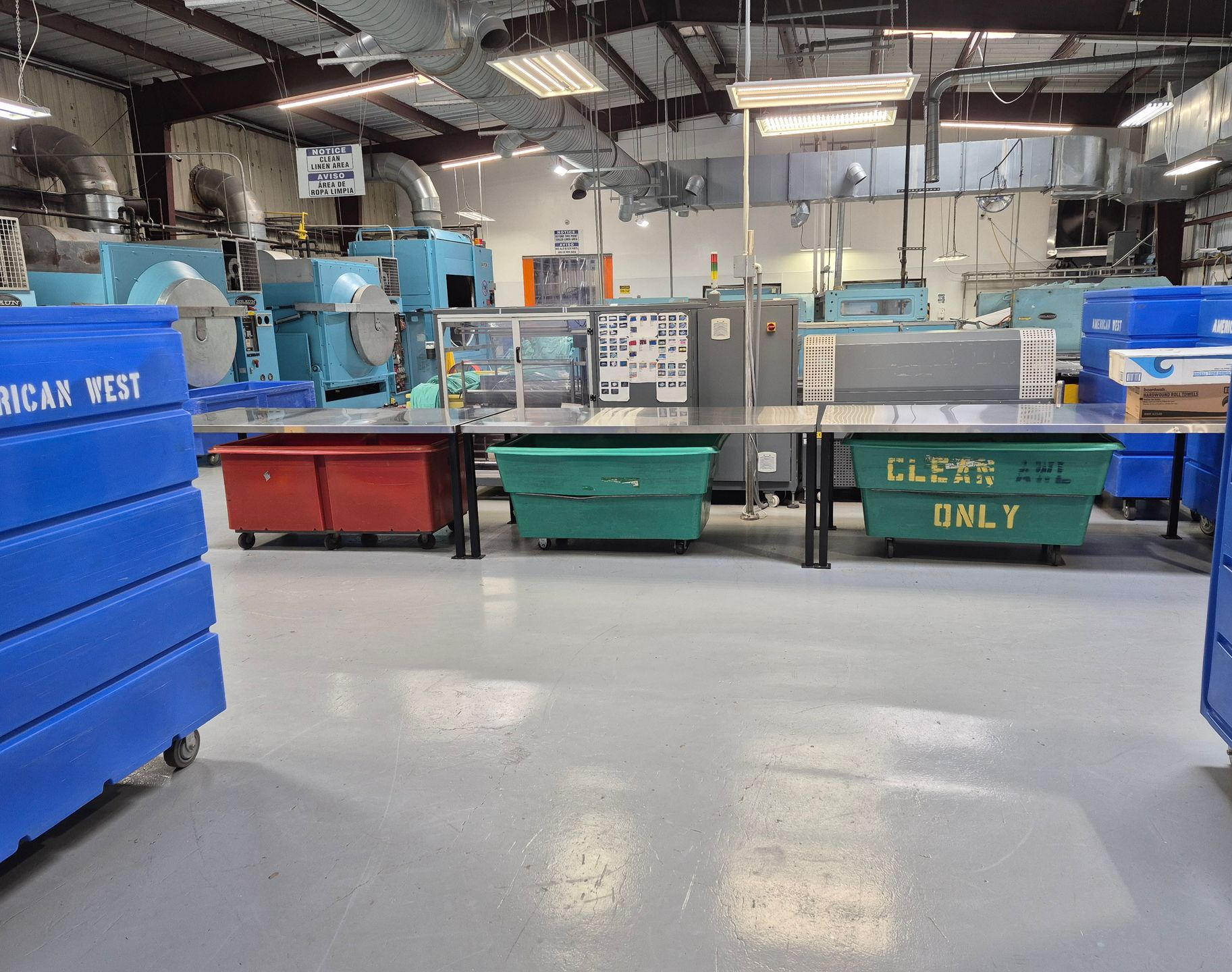 Factory interior with blue and green bins, machinery, and work tables.