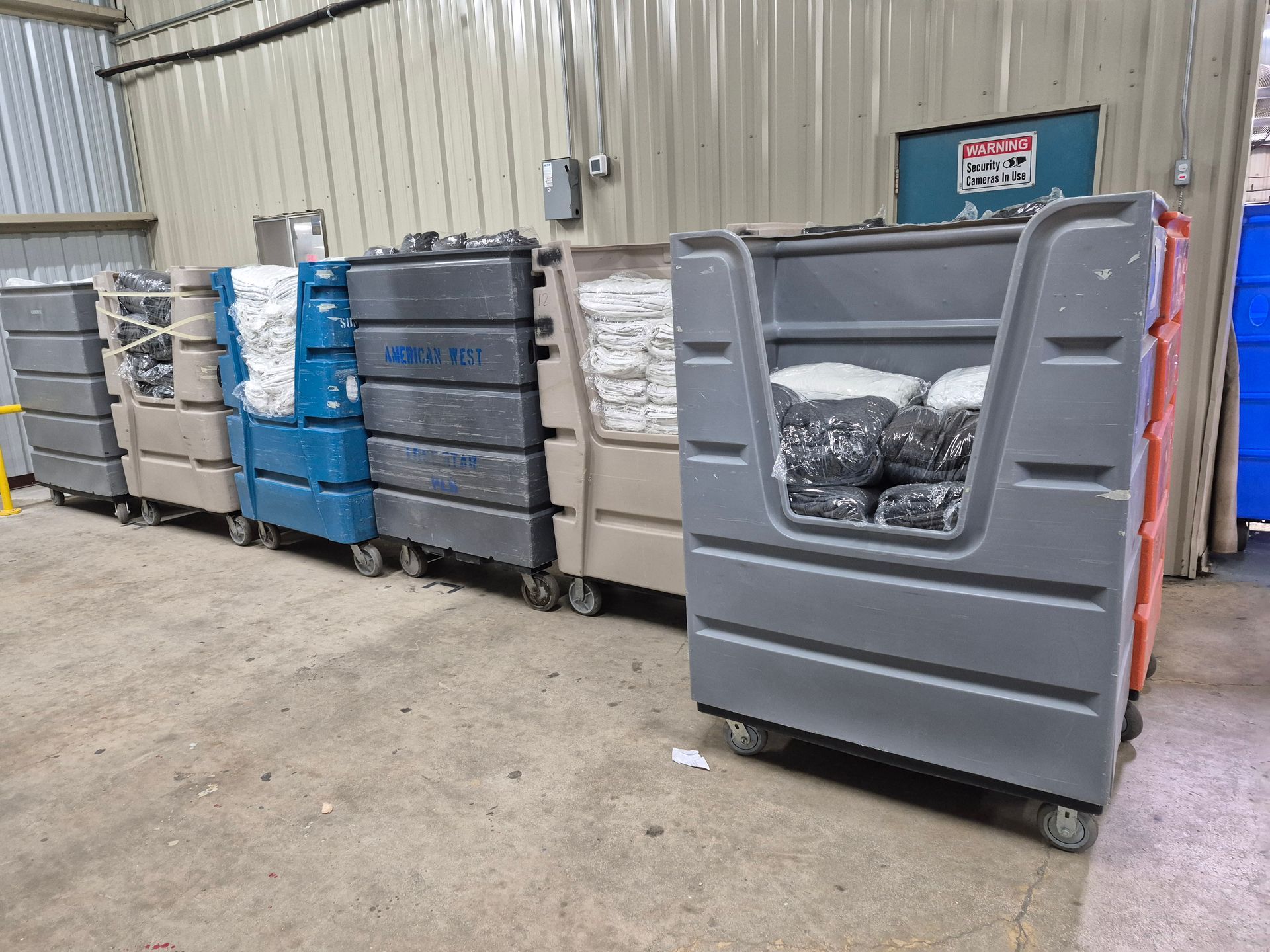 Laundry carts filled with white and black garments, lined up in a warehouse setting.