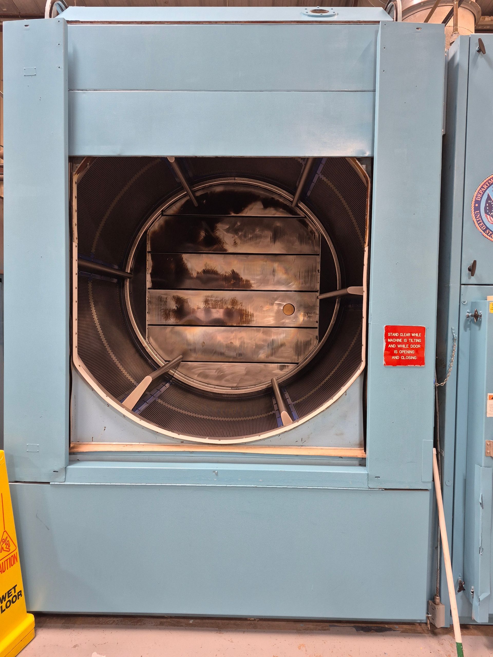 Blue industrial fan with large circular grill, containing square metal plates.