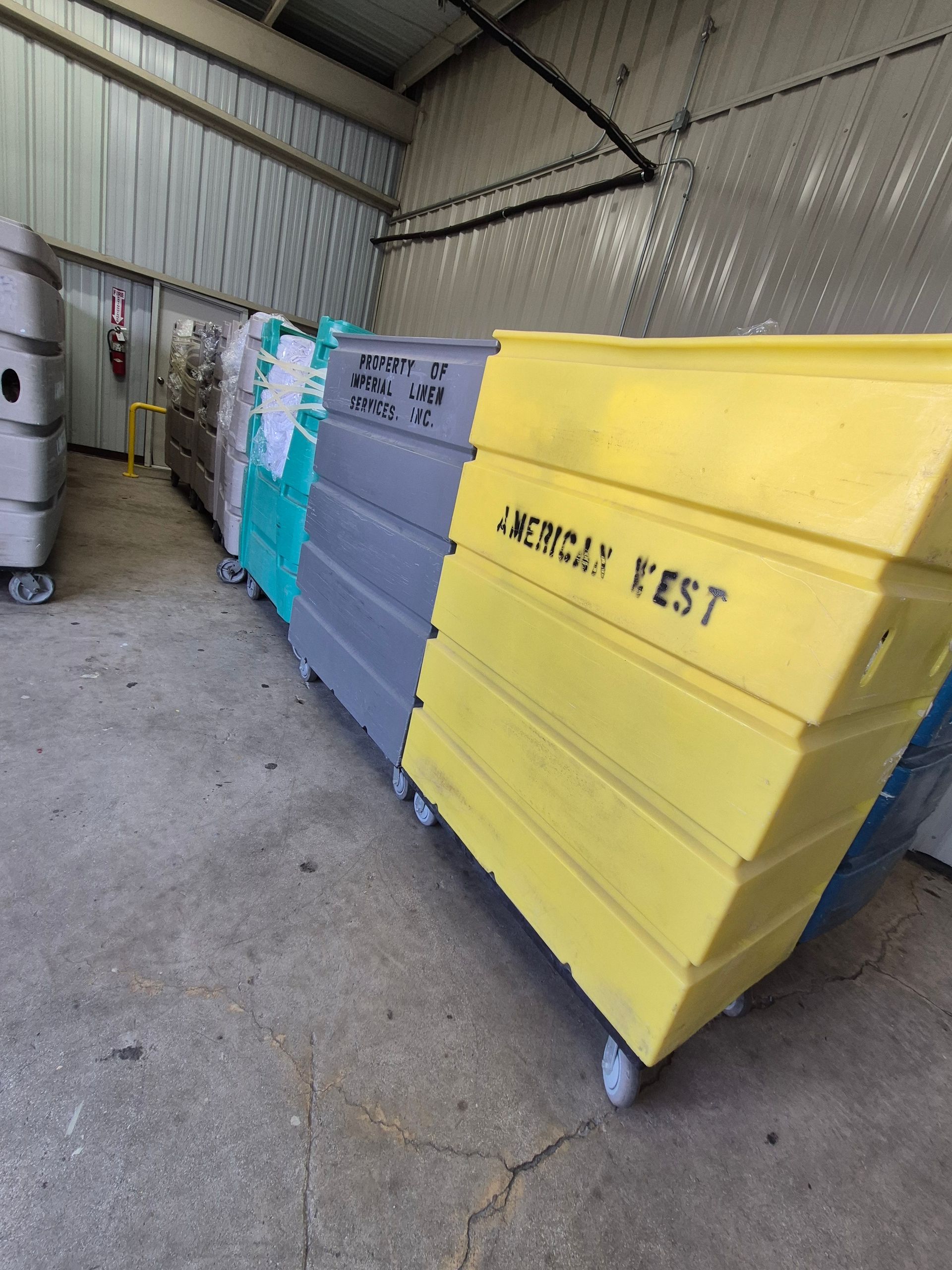 Laundry carts filled with linens in an industrial facility, under a metal roof.