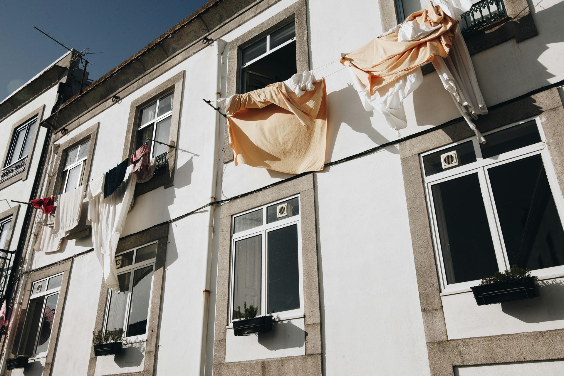 White building with windows; laundry hangs outside.