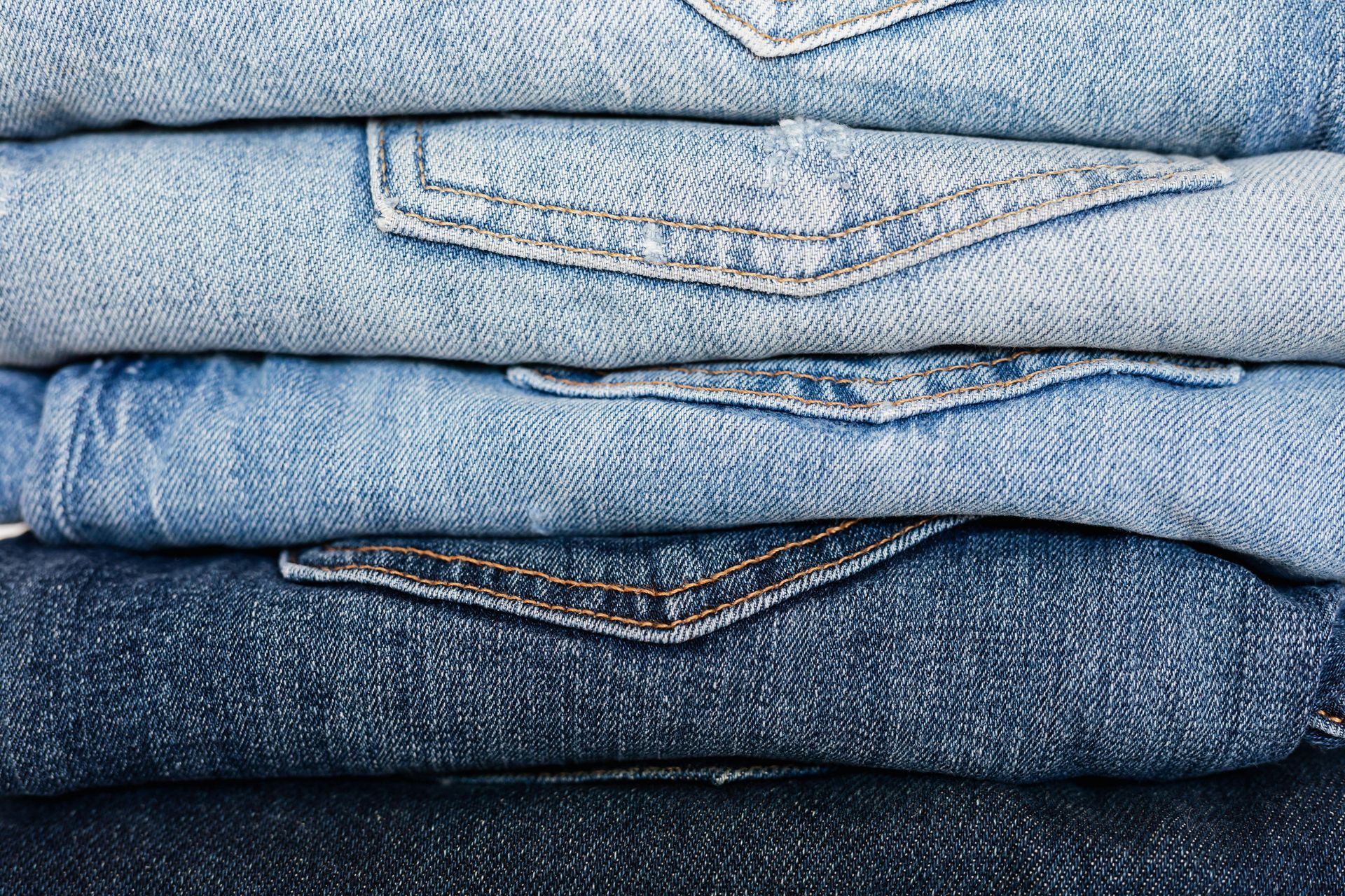 Stack of folded denim jeans in various shades of blue.