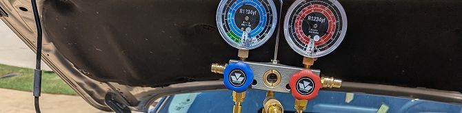 A bunch of gauges are sitting under the hood of a car. | Compassion Auto Care LLC