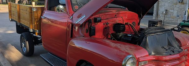 A red truck with the hood up is parked on the side of the road. | Compassion Auto Care LLC