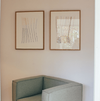Art in picture frame hung on wall above chair