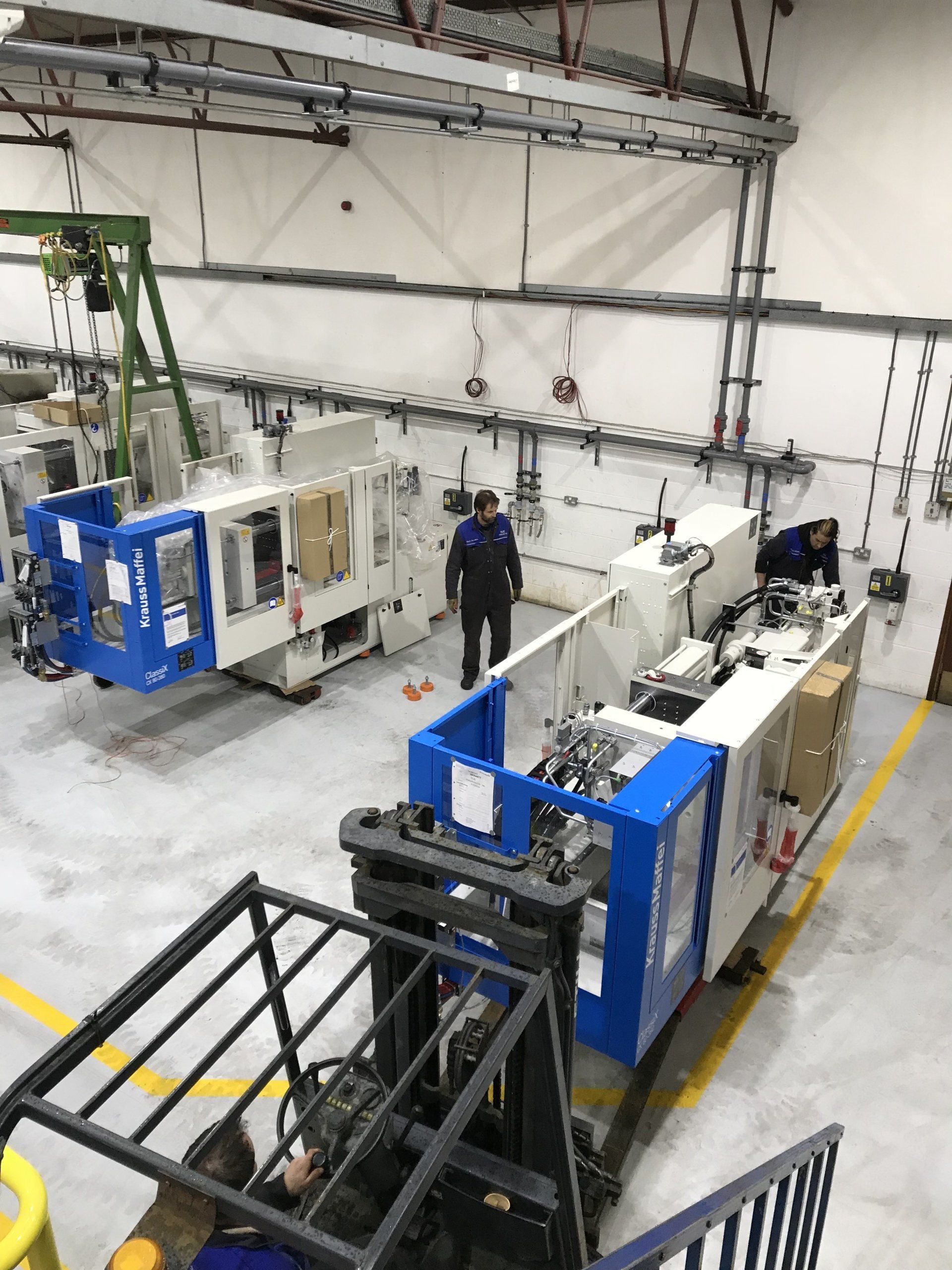 A forklift is moving a machine in a factory.