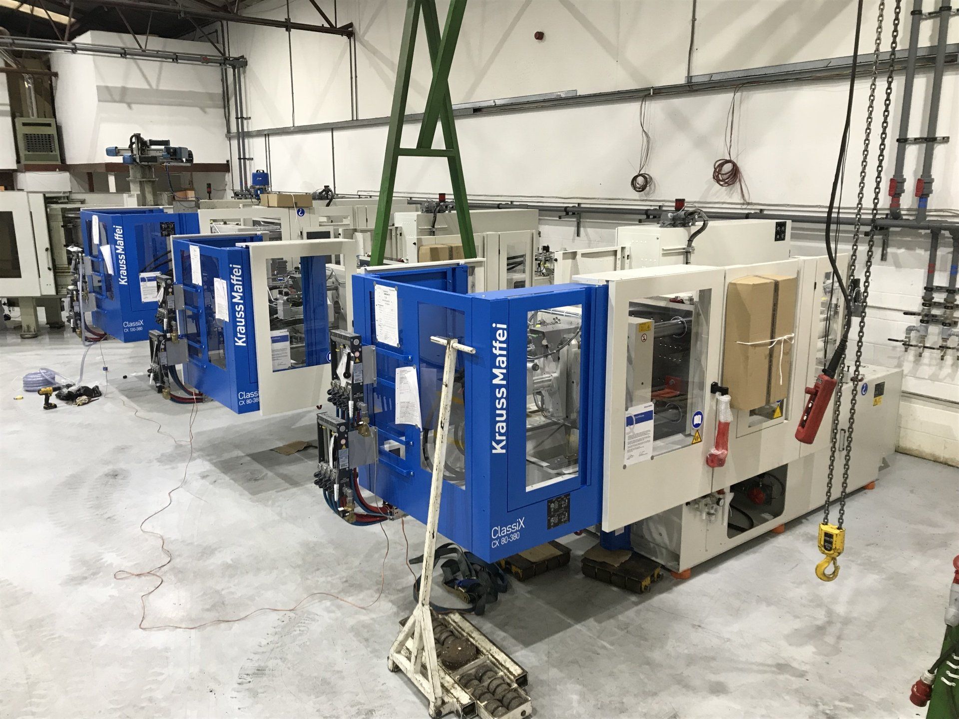 A row of injection molding machines are lined up in a factory.