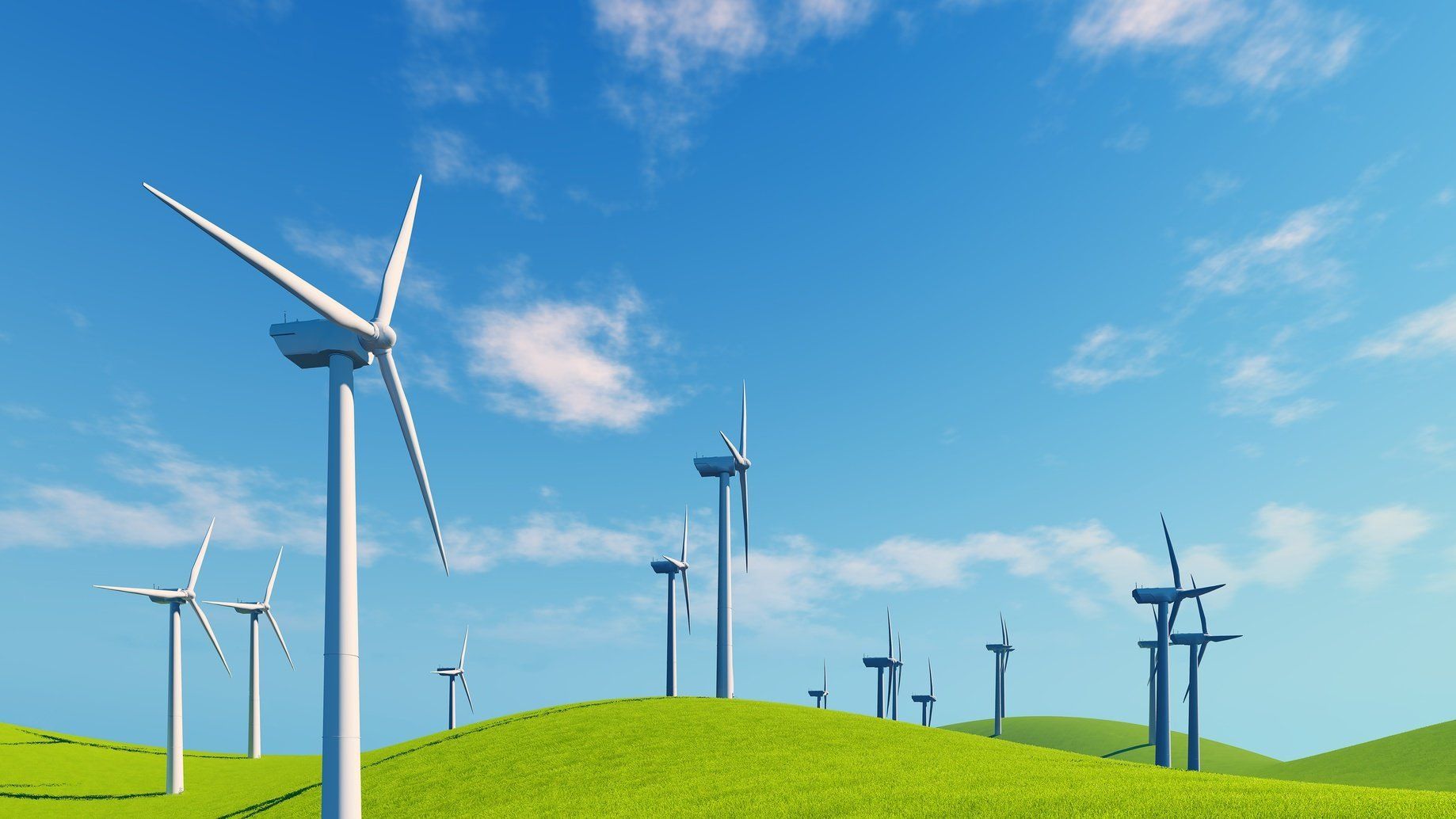 A row of wind turbines are sitting on top of a grassy hill.