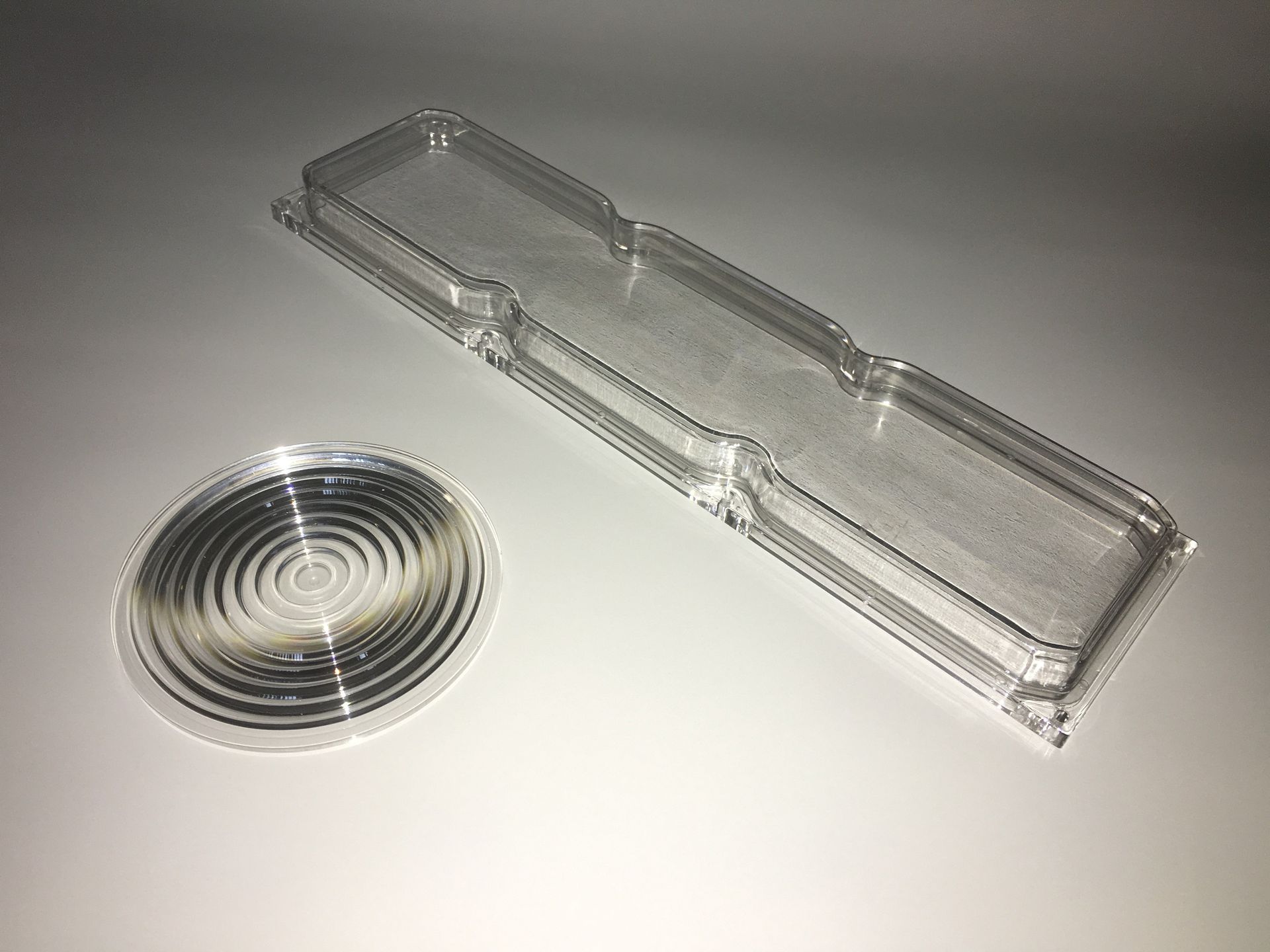 Two clear plastic objects are sitting on a white surface.