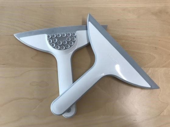 Two squeegees are sitting on top of each other on a wooden table.