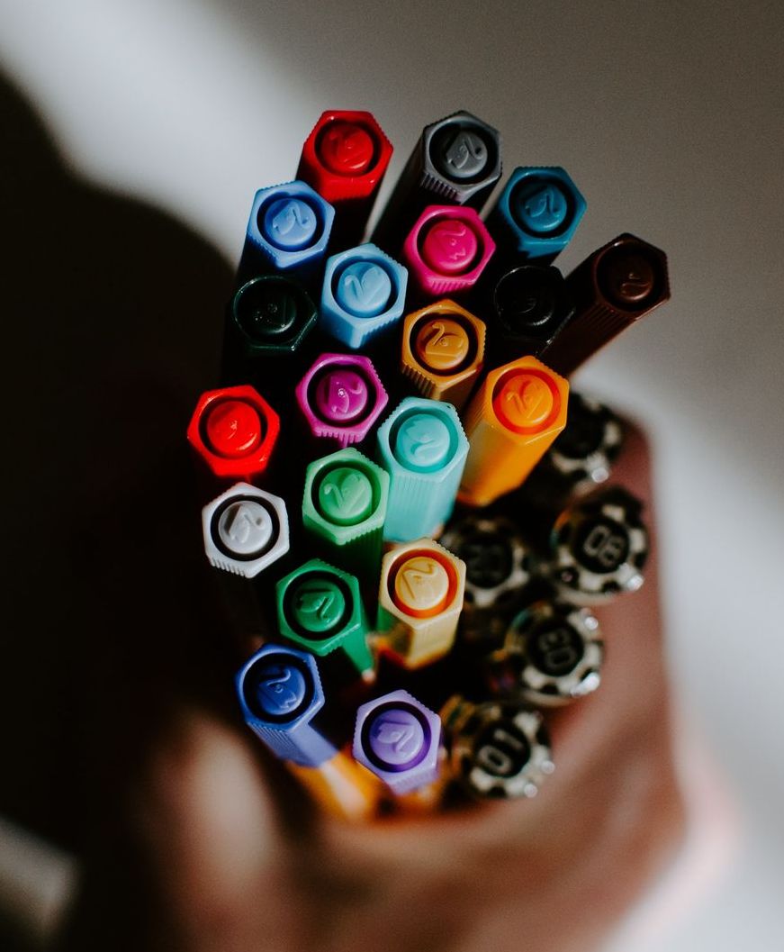 A person is holding a bunch of markers in their hand