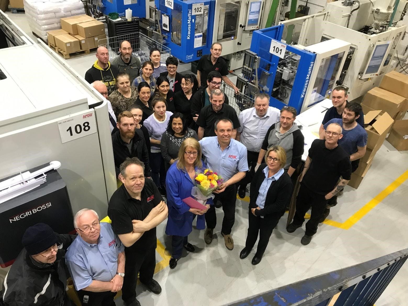 A group of people are posing for a picture in a factory.