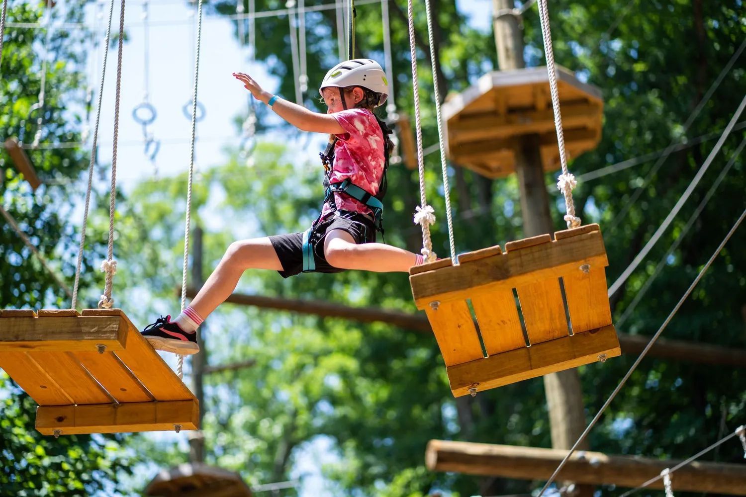 A young girl is flying through the air on a ropes course at the Flying Rabbit.