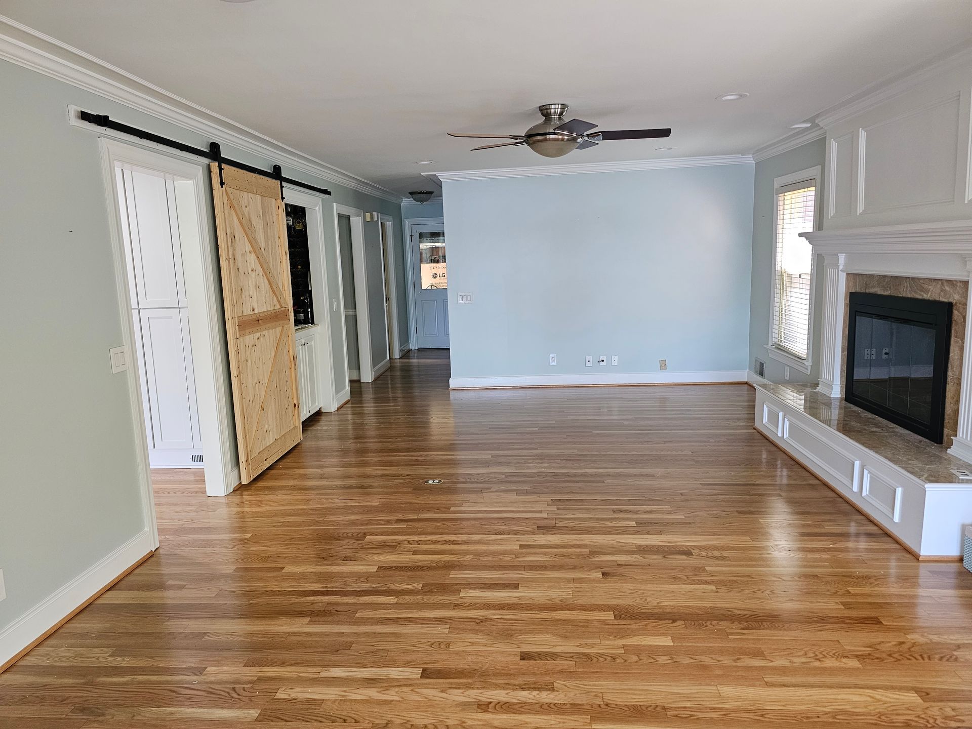 Spacious living room with hardwood floors, blue walls, fireplace, and barn doors.