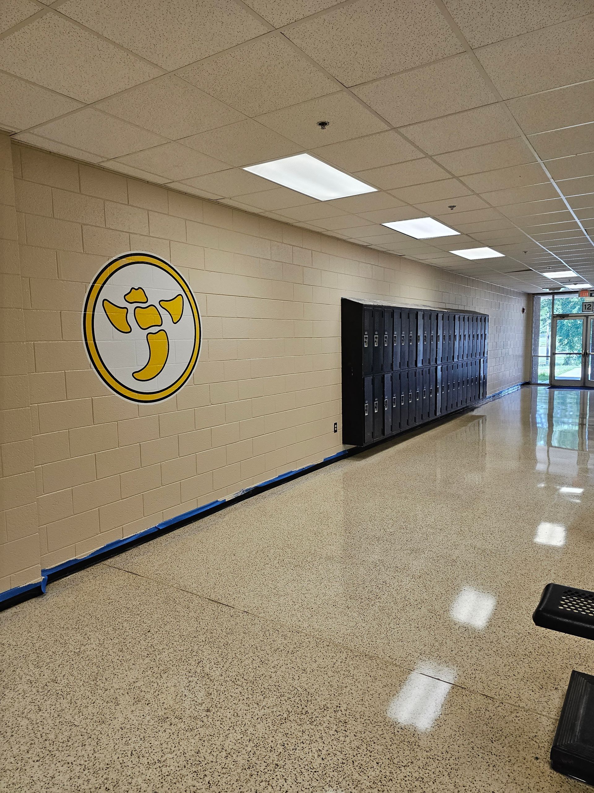 School hallway with lockers on the right and a school logo on the left.
