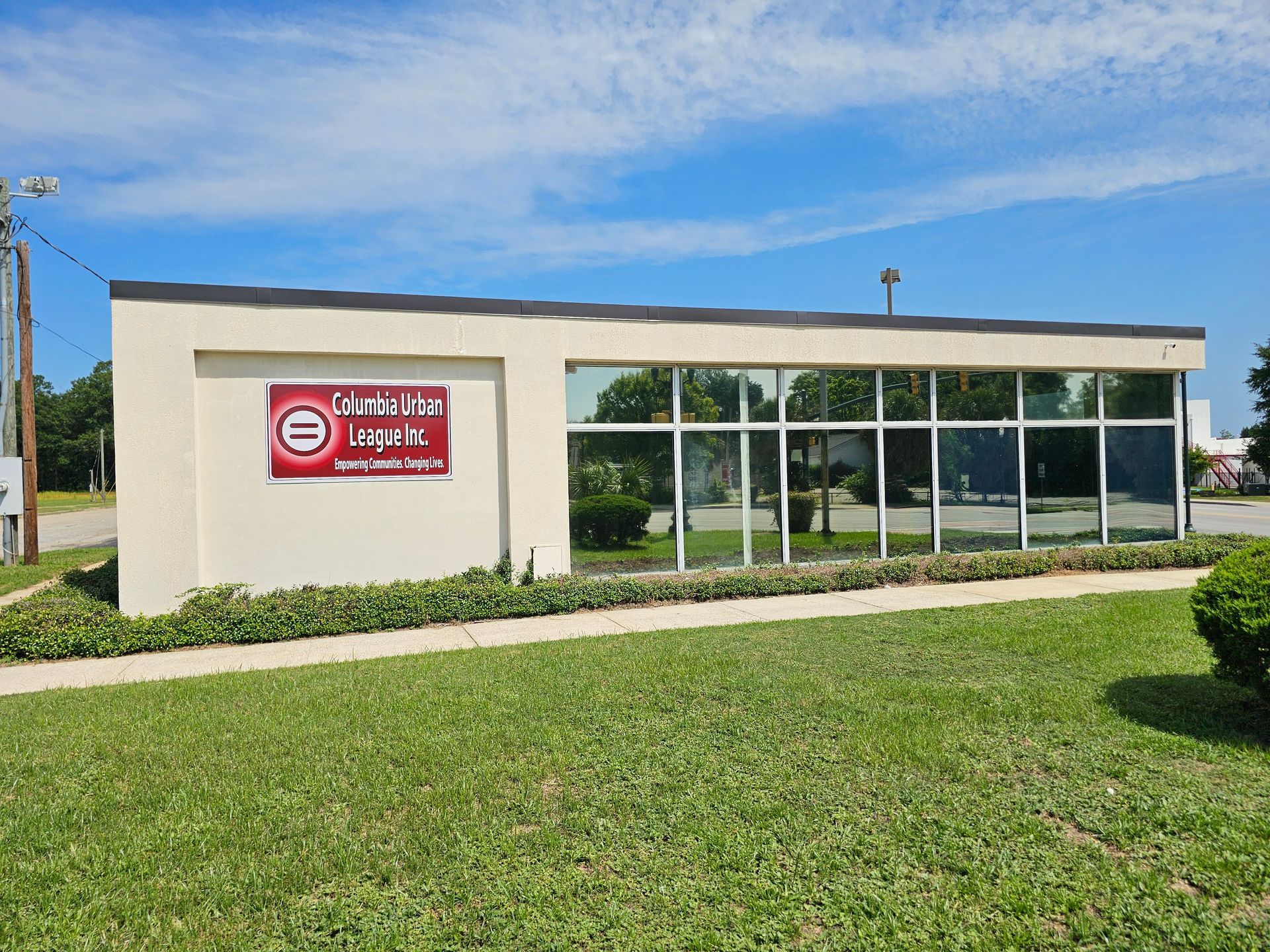 Exterior of Columbia Bank branch with sign and large windows, green lawn, blue sky.