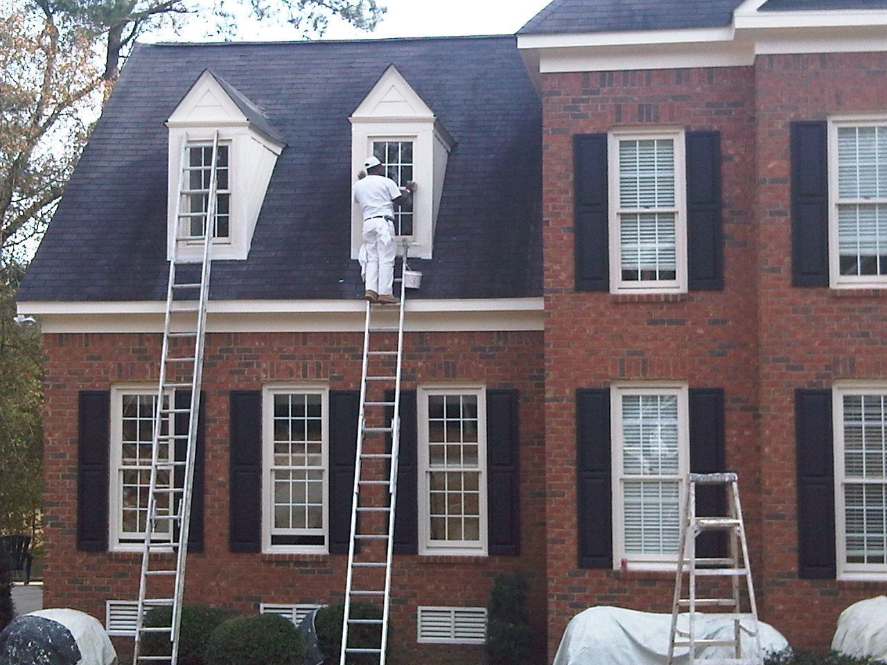 Hallway with speckled floor, tan walls, exit sign, and painting supplies.