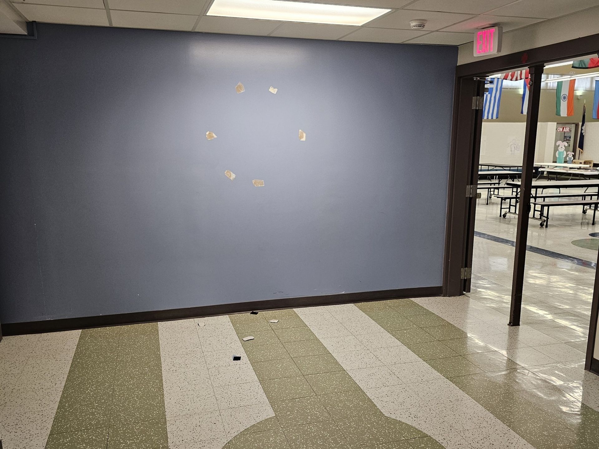 Blue wall with light-colored speckle floor, open doorway to a cafeteria.