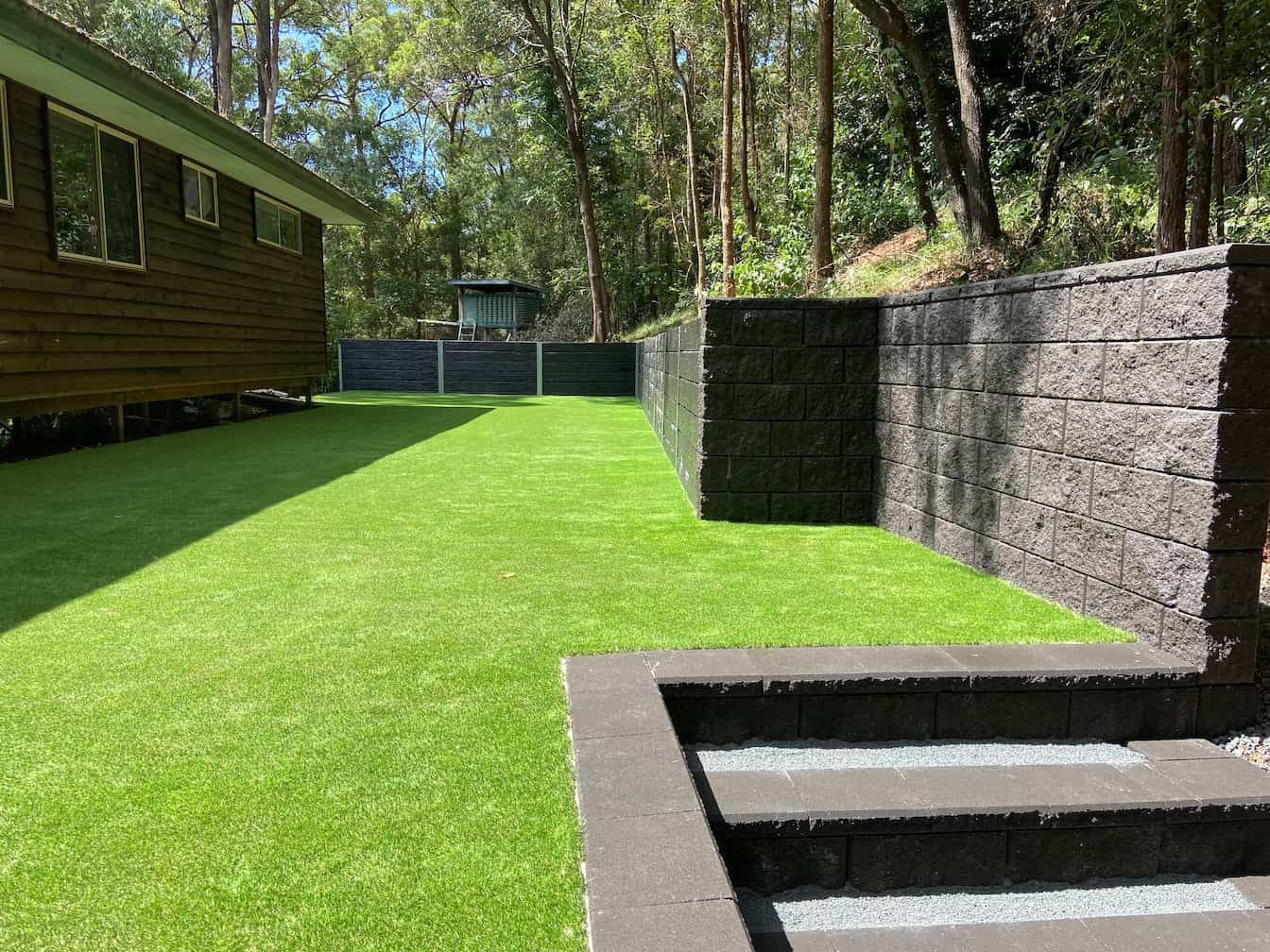 a backyard with artificial turf with a fence and stairs leading up to it 