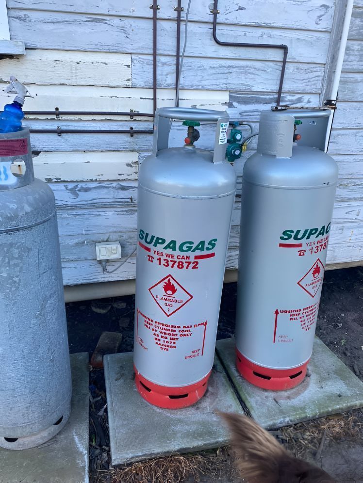 Two Propane Tanks Are Sitting Next To Each Other In Front Of A Building — Casino Plumbing In Casino, NSW