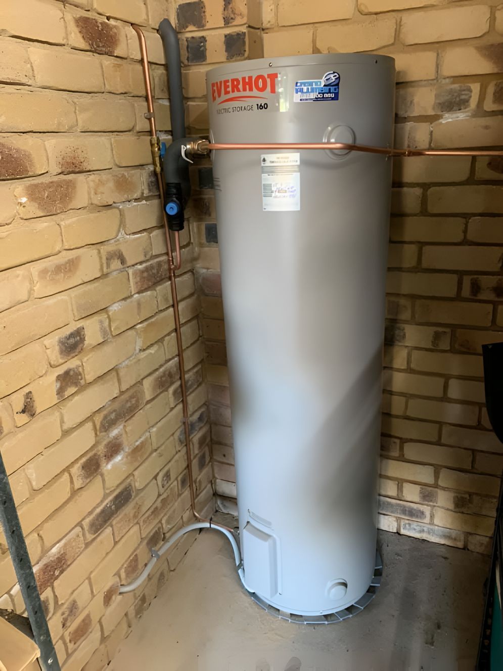 A Water Heater Is Sitting In A Room Next To A Brick Wall — Casino Plumbing In Casino, NSW