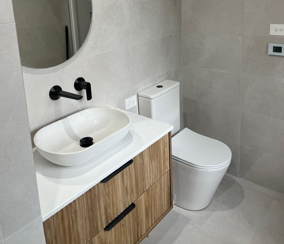 A Toilet With A Blue Seat And A Hand Rail In A Bathroom — Casino Plumbing In Casino, NSW