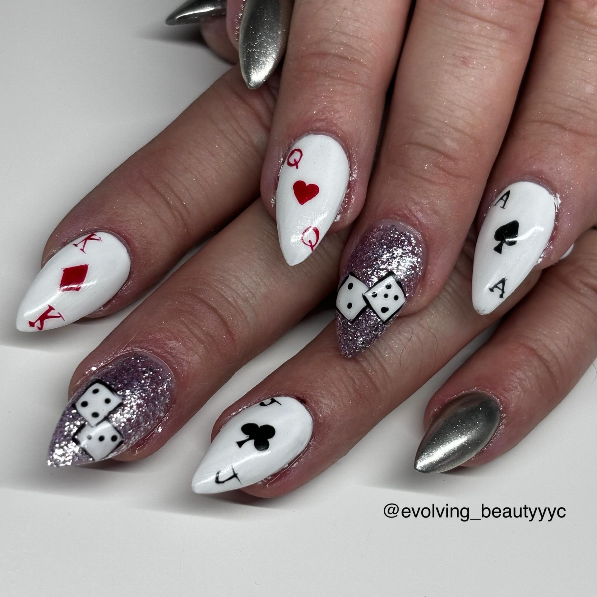 A woman 's nails are decorated with playing cards and dice
