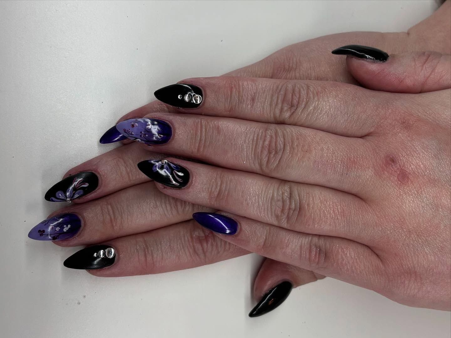 A close up of a woman 's hands with black and purple nails