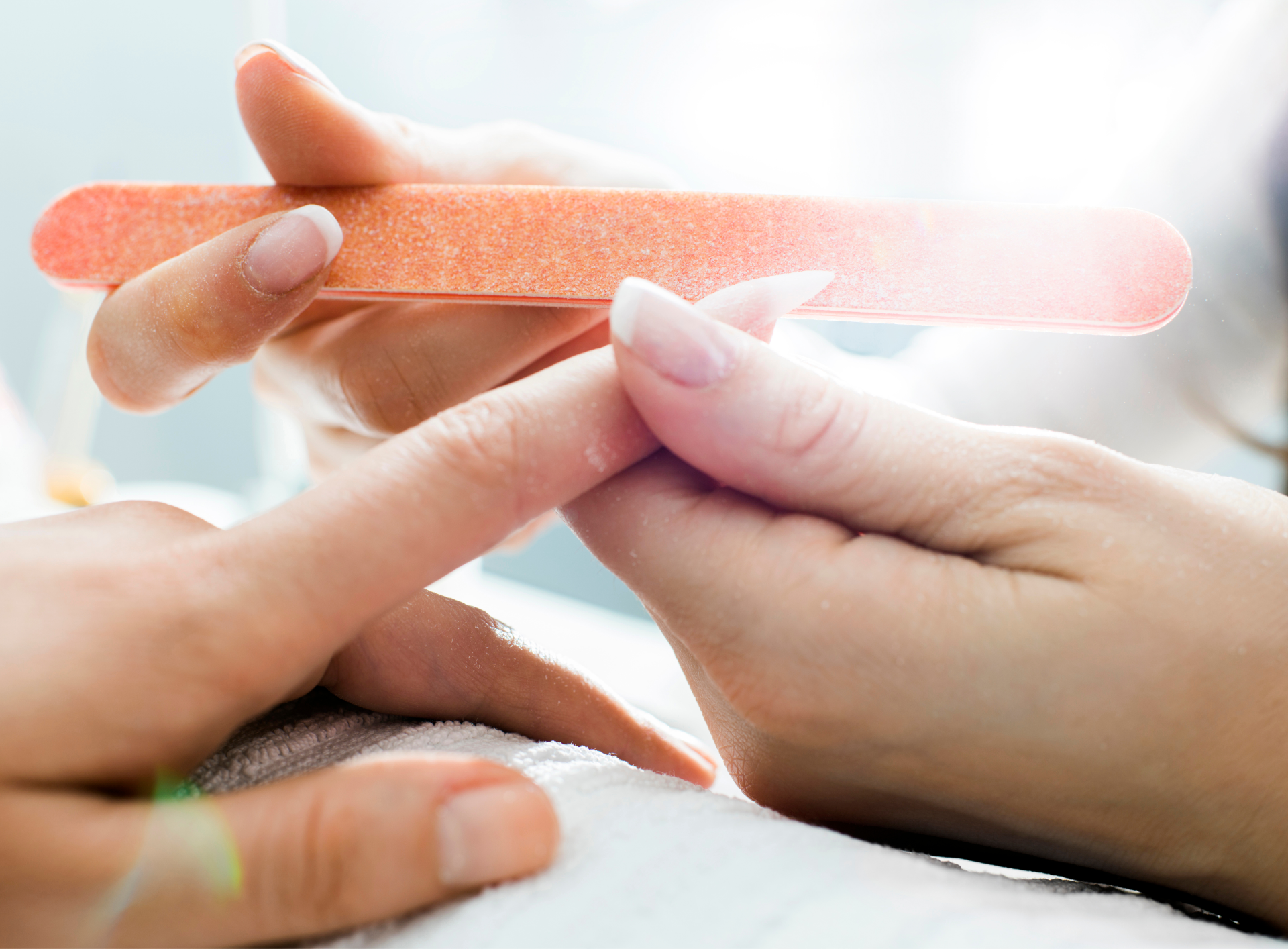 A woman is getting her nails done by a nail file.