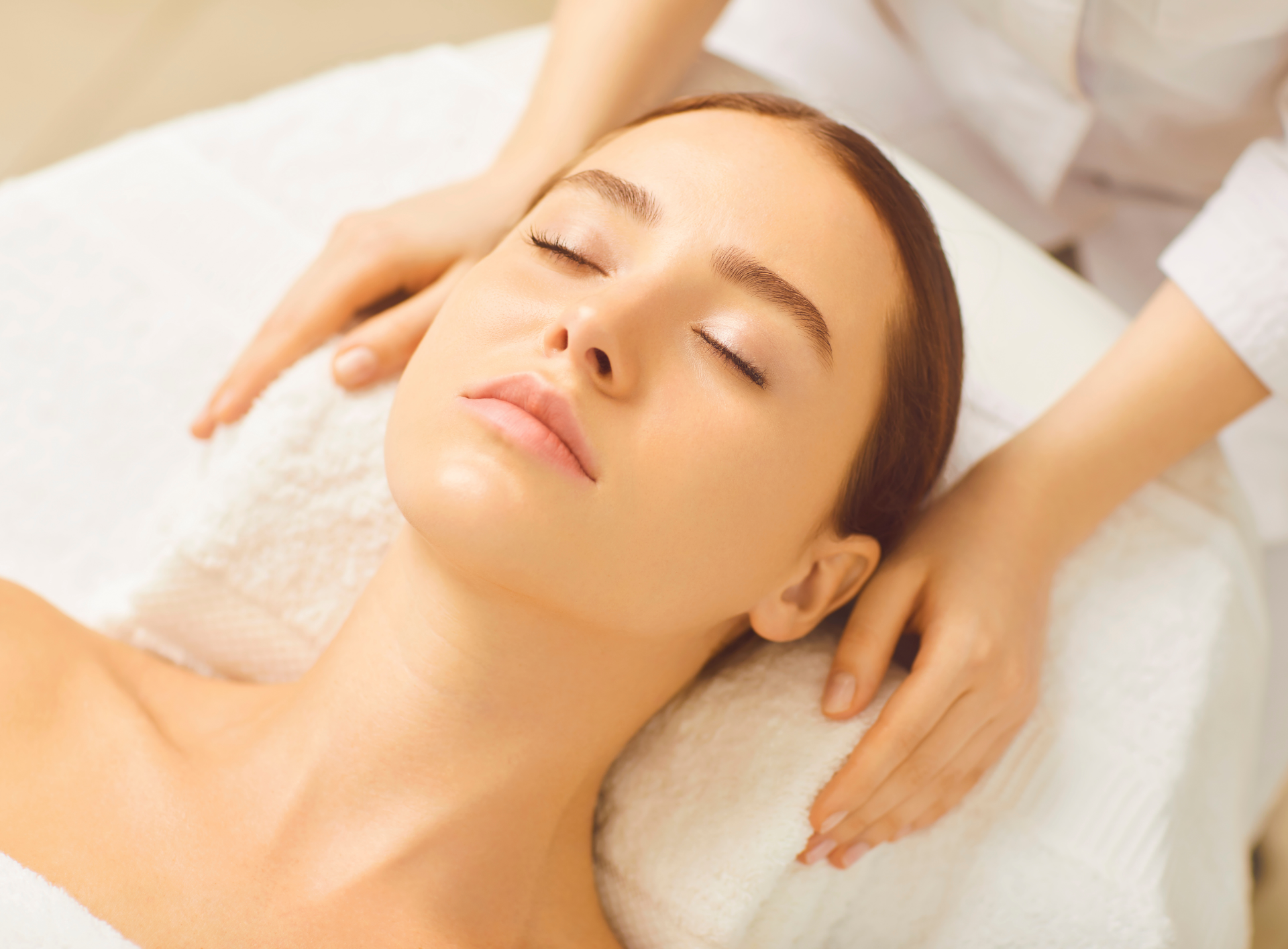 A woman is getting a massage at a spa with her eyes closed.