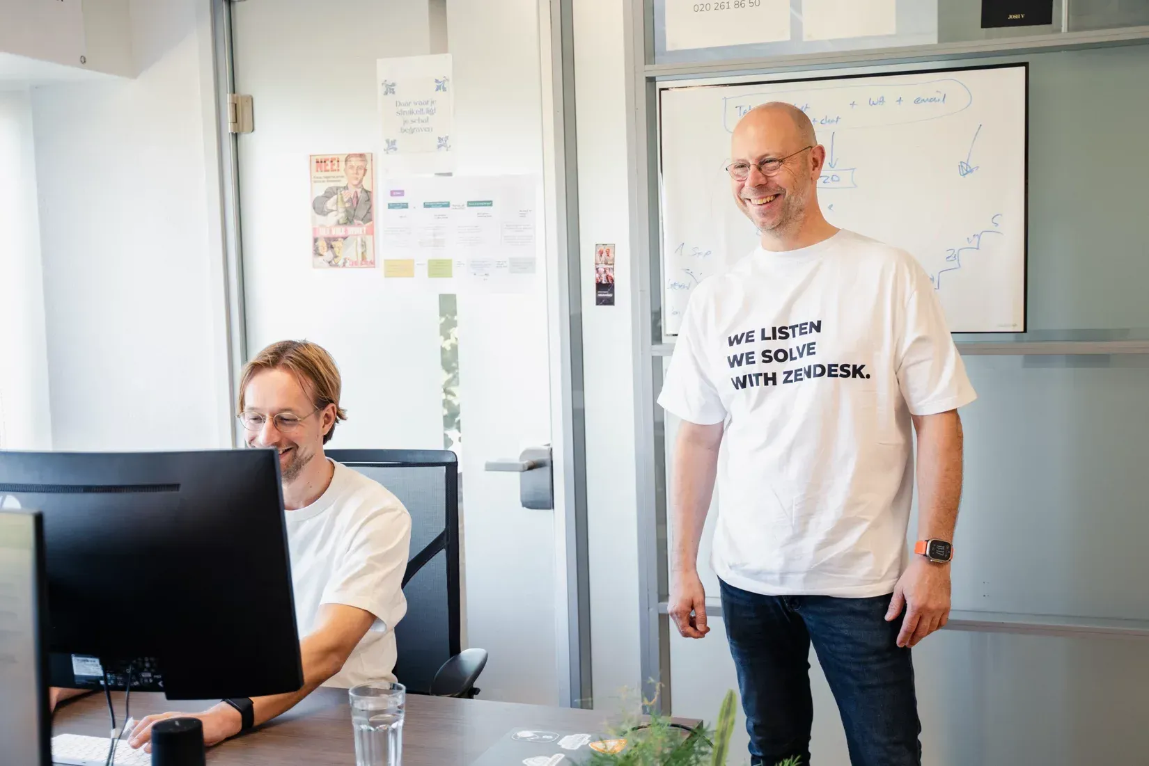 Een vrouw met een koptelefoon op praat met een mobiele telefoon in een callcenter.