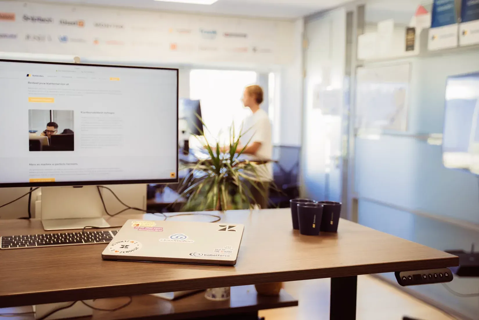 Een vrouw zit aan een bureau voor een computerscherm.