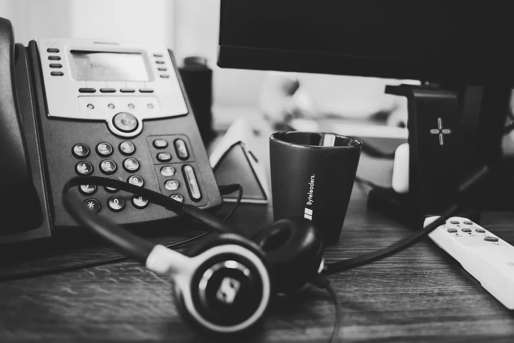Een zwart-witfoto van twee personen die met laptops aan een tafel zitten.