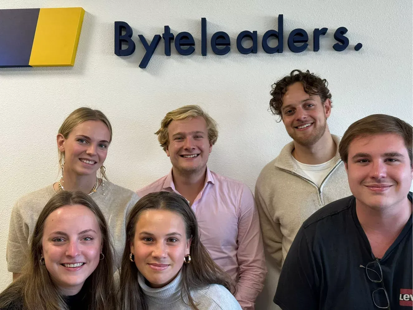 A group of people are posing for a picture in front of a sign that says byte leaders.