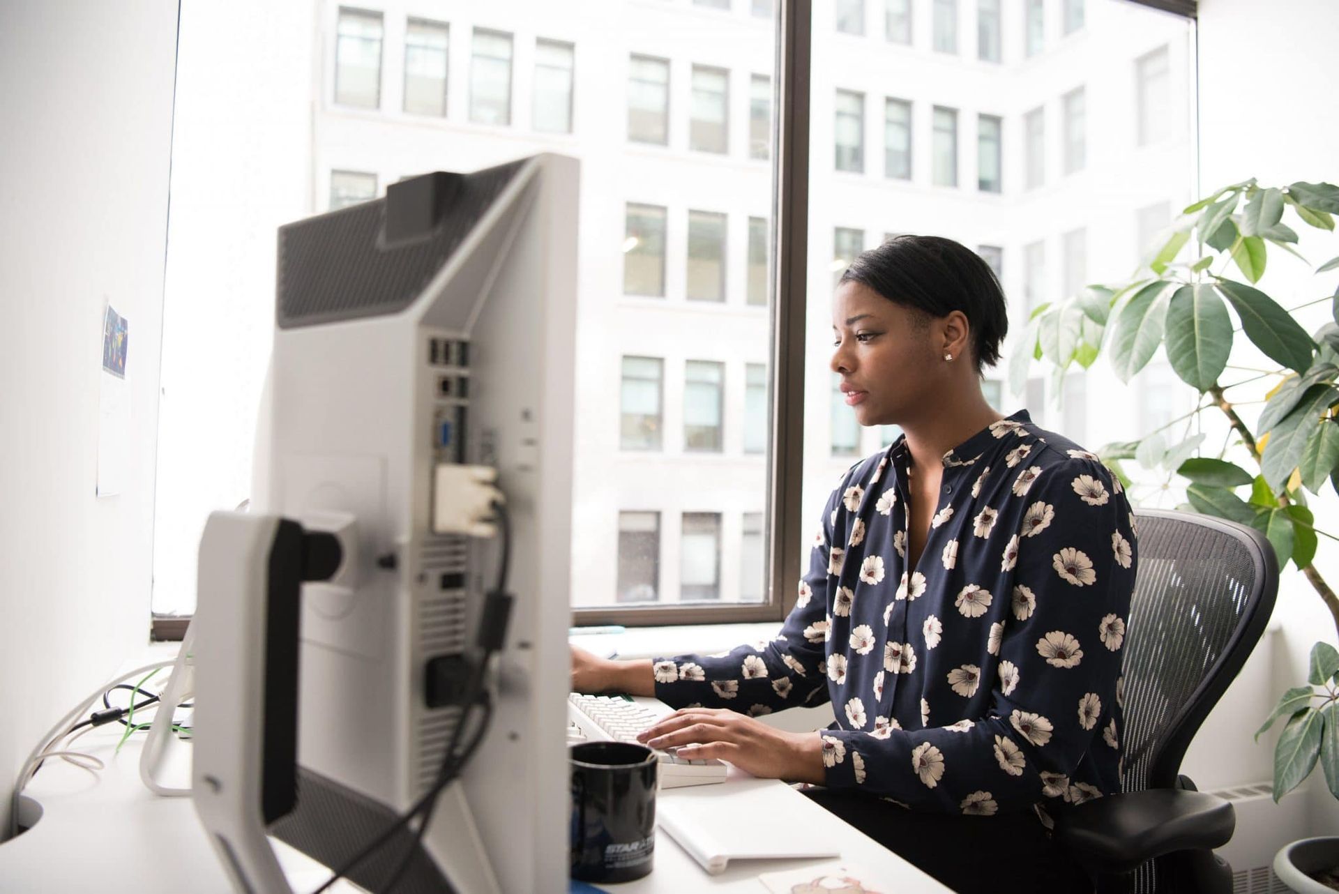 Een vrouw zit aan een bureau voor een computerscherm.