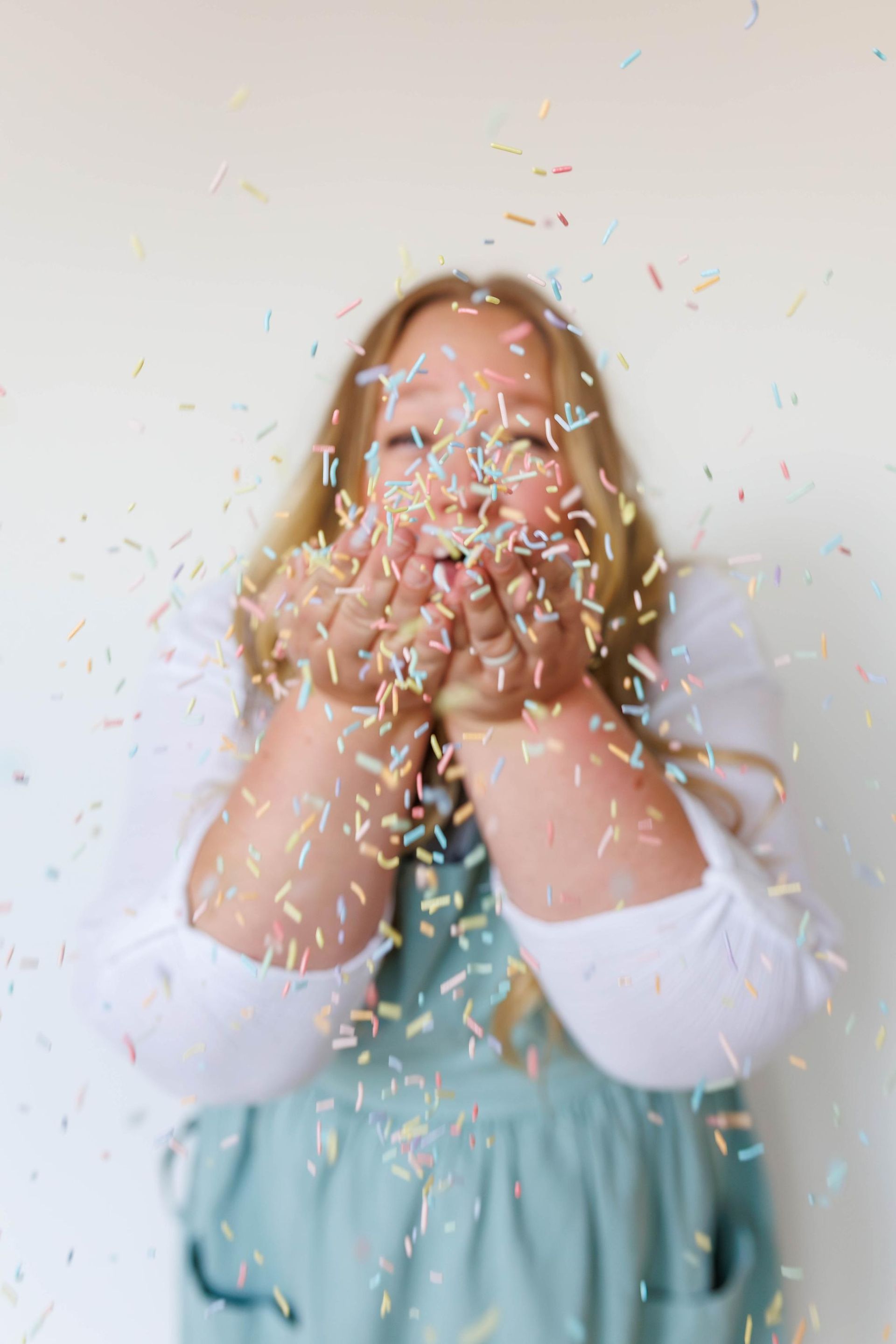 Person blowing colorful sprinkles from hands.