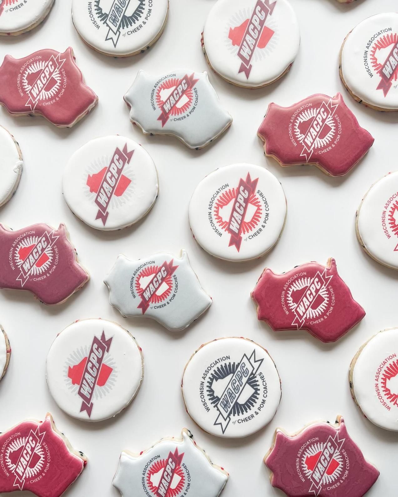 Cookies decorated with logos in red, gray, and white arranged on a white surface.