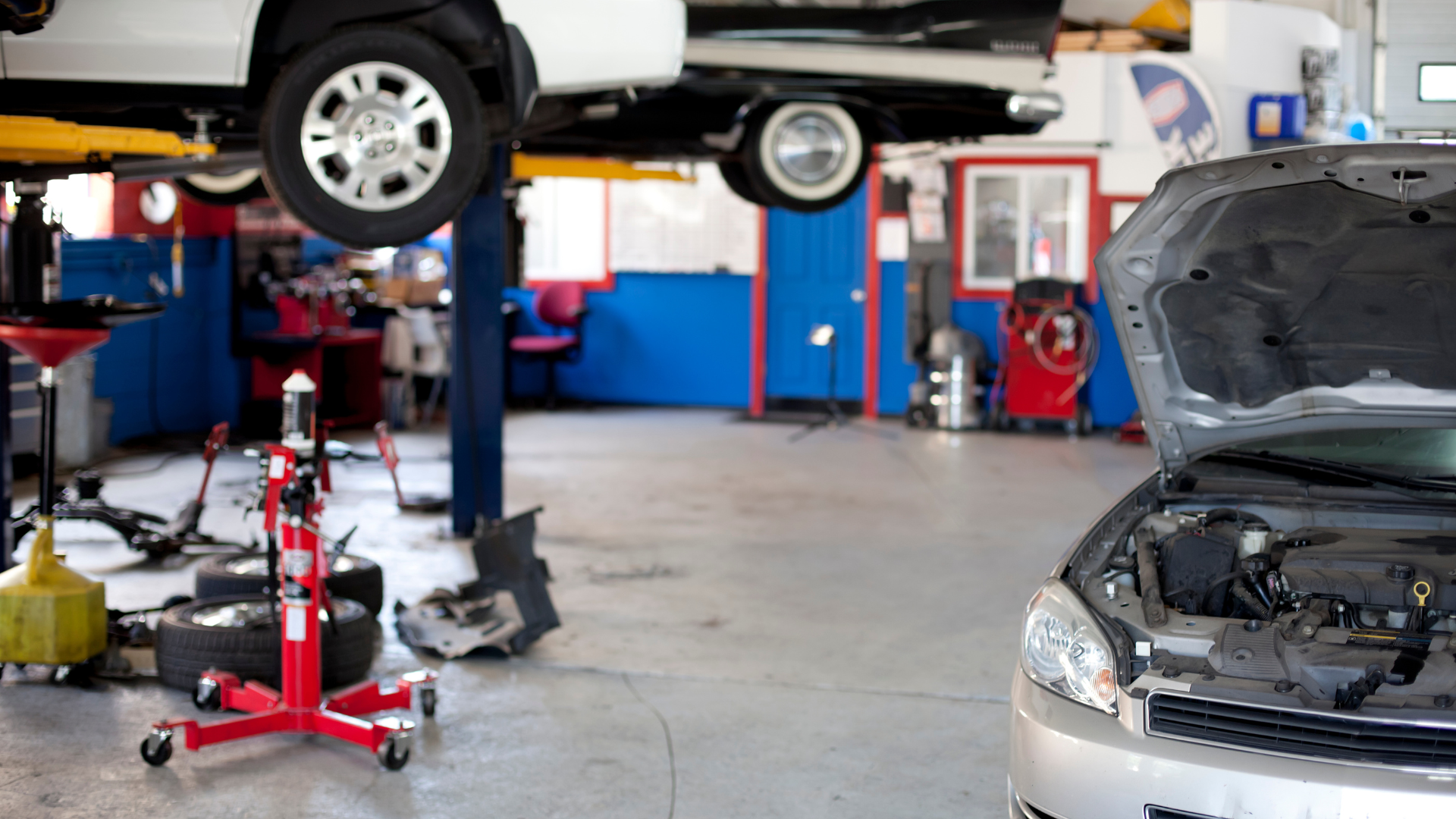 A car is sitting on a lift in a garage with the hood open.