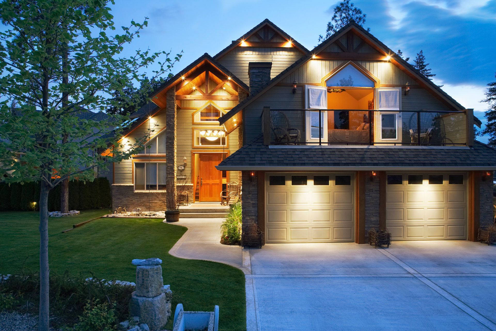 A large house is lit up at night and has two garage doors