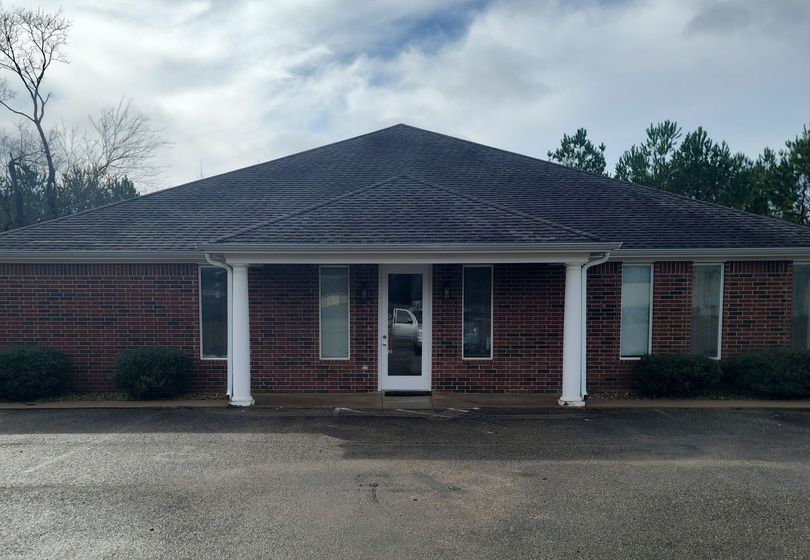 A brick building with a gray roof and a white door