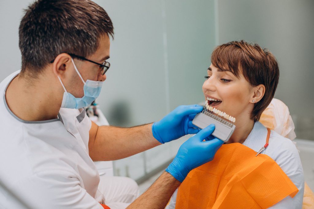 A dentist is examining a woman 's teeth in a dental office.