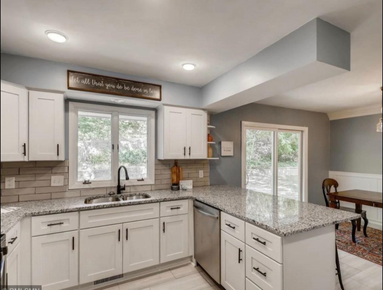 White kitchen with granite countertops, stainless steel appliances, and a window.