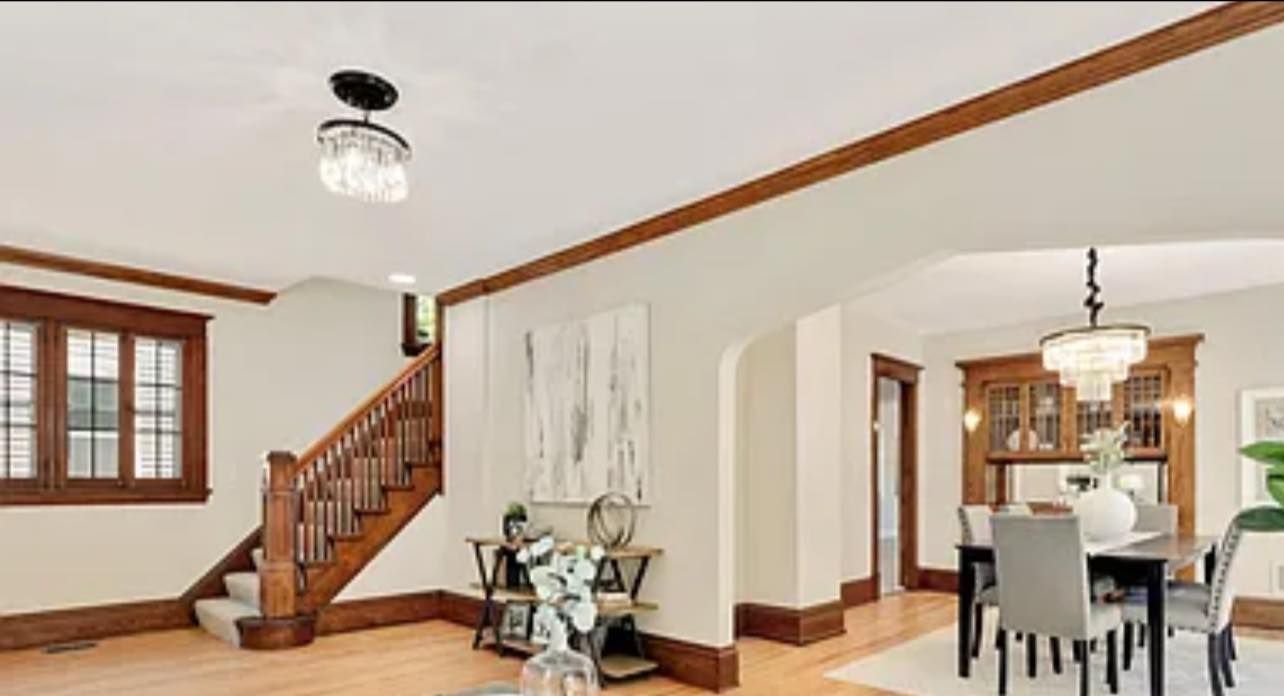 Entryway with staircase, dining room archway, and wood trim. Neutral walls with light wood floors.