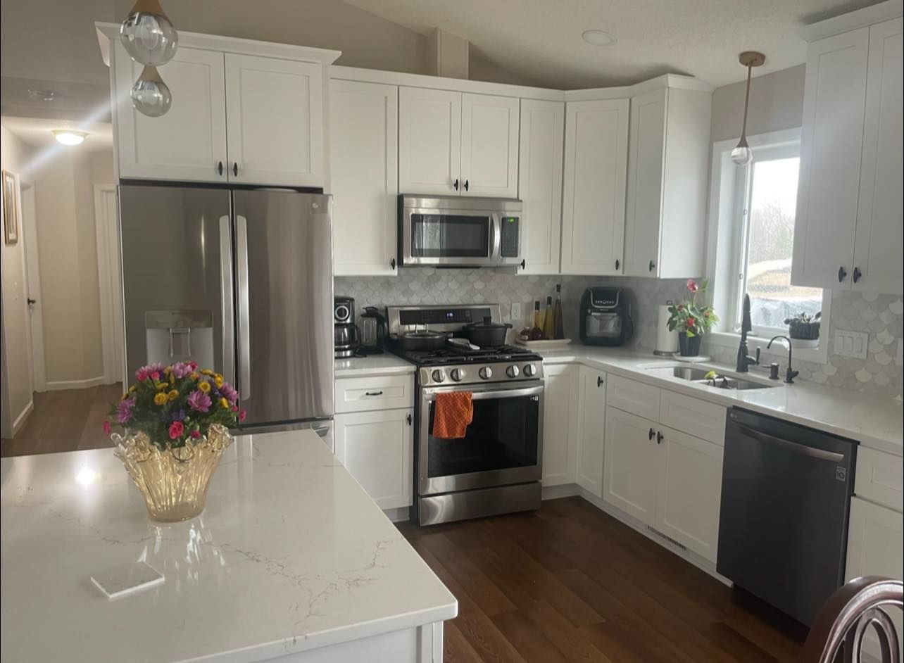 White kitchen with stainless steel appliances, white cabinets, and a white countertop island.