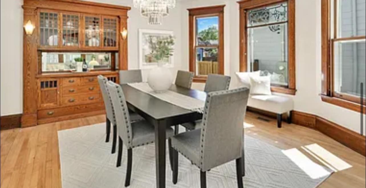 Dining room with dark table, gray chairs, wooden built-in cabinet, and natural light.
