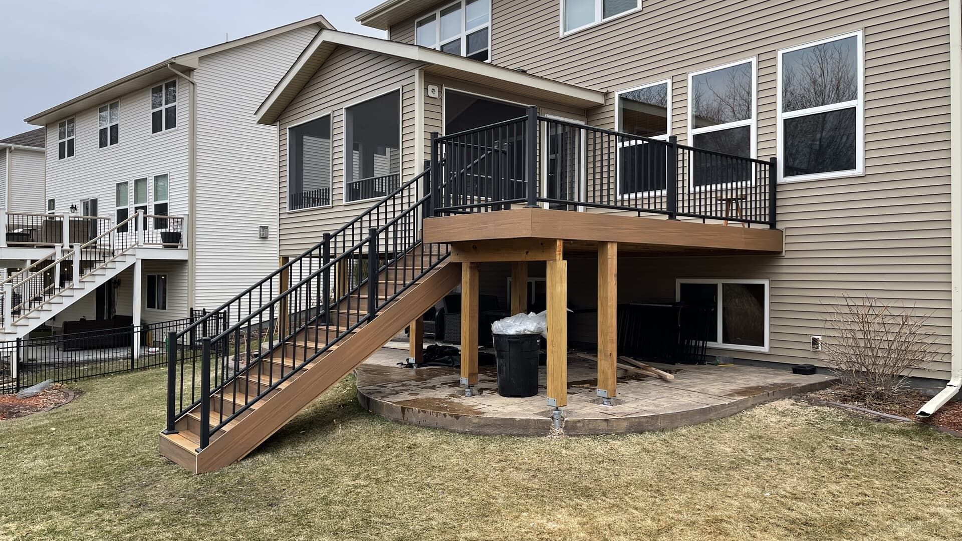 Backyard with a raised deck, stairs, and a screened-in porch, beige siding, and brown railings.
