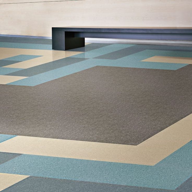 Geometric patterned floor in gray, blue, and tan, with a dark bench against a wall.
