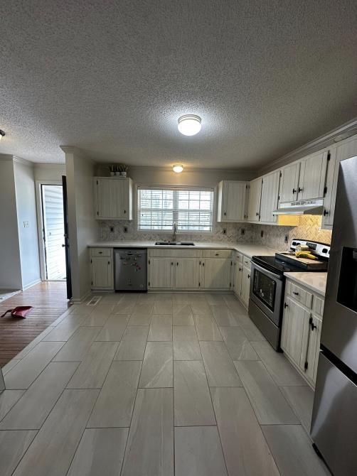 Kitchen with white cabinets, stainless steel appliances, and light tile floor.